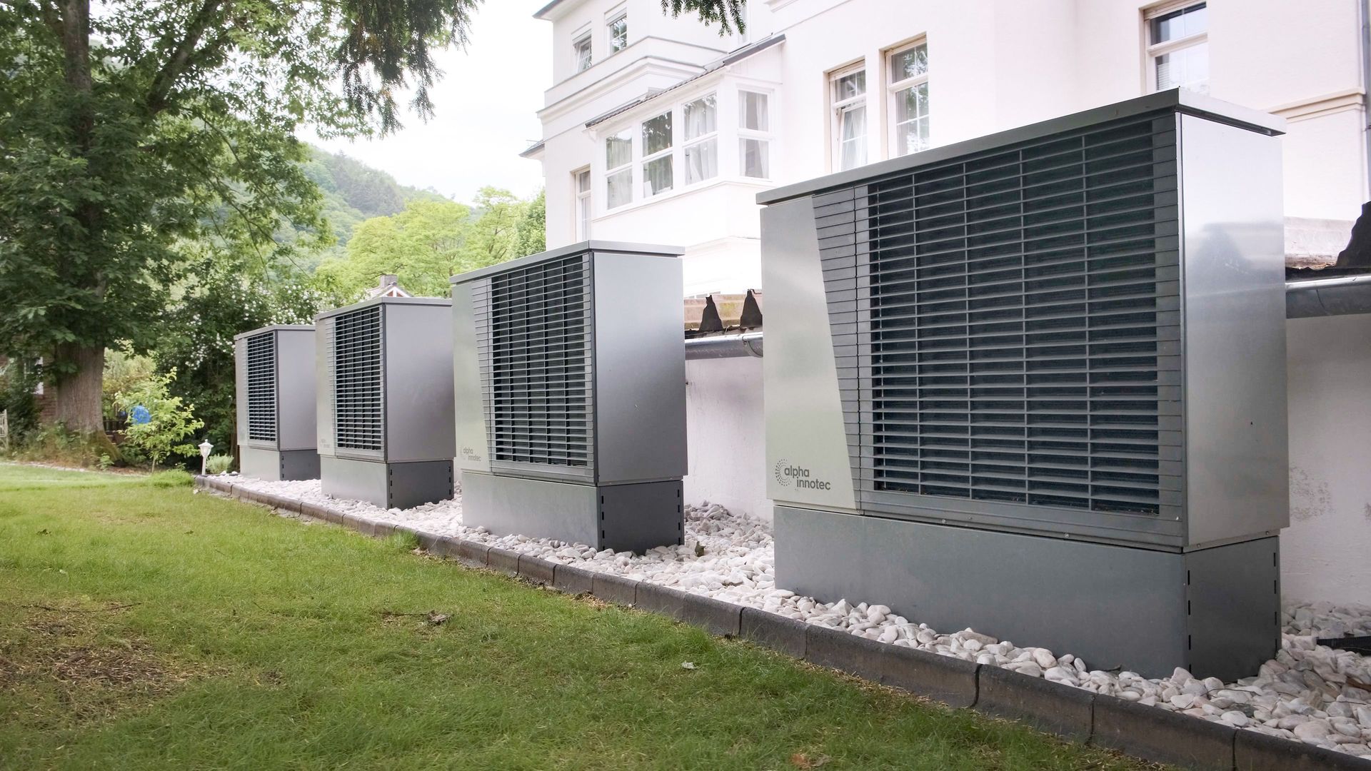 Row of heat pumps outside a building promoting sustainable energy solutions.